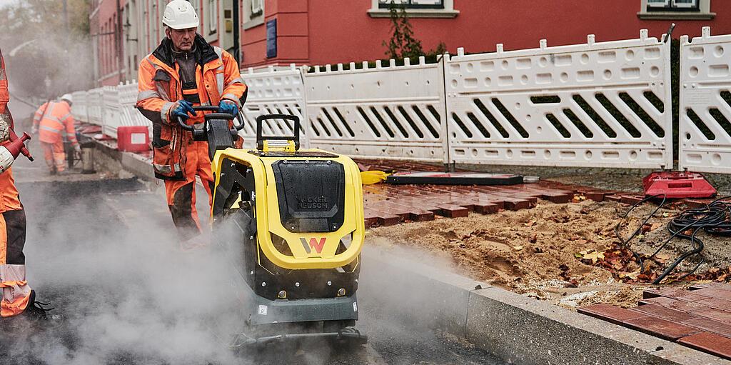 construction worker working with vibratory plate at inner city construction site