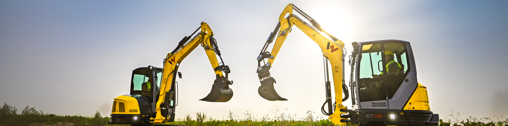 Two Wacker Neuson tracked excavators standing on a construction site.